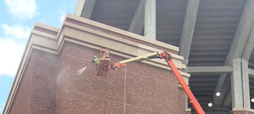 Washer Power's pressure washer services in Bryan and college station power cleaning the exterior of a brick building.
